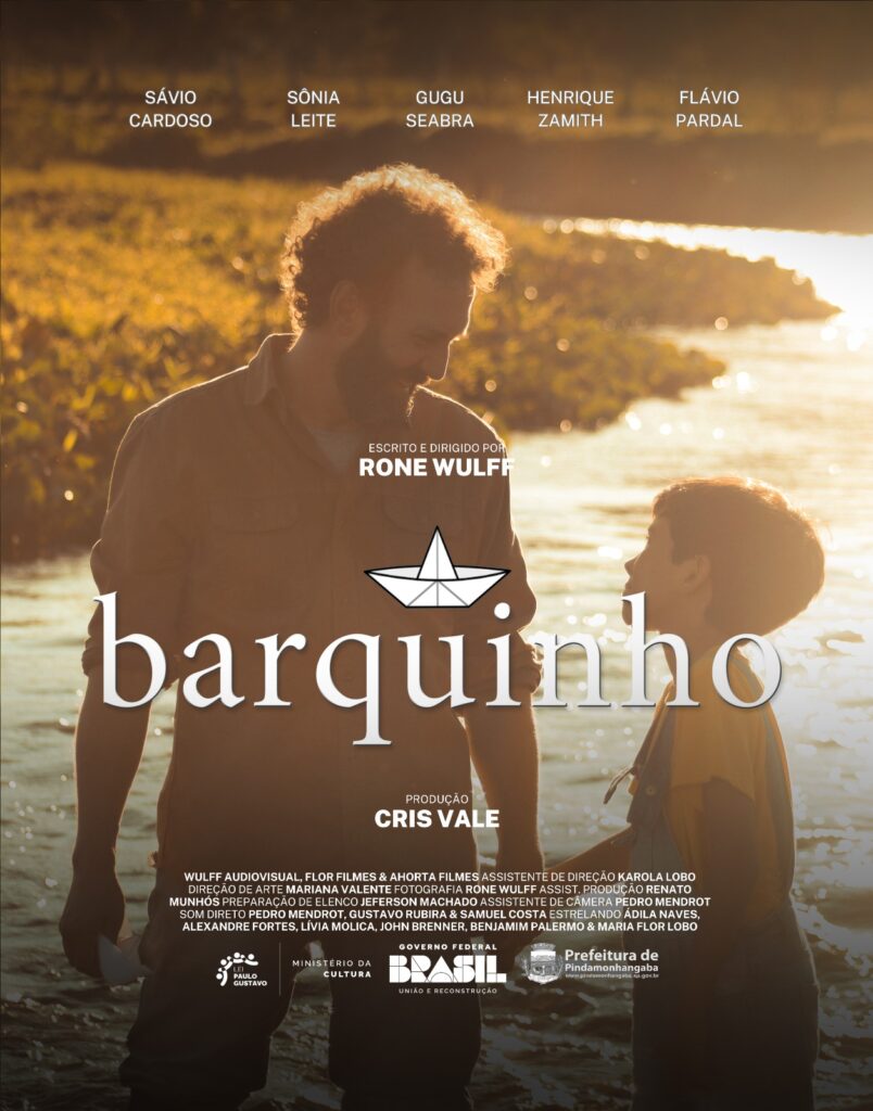 Poster do filme barquinho, com uma fotografia onde um home e uma criança andam de mãos dadas como pai e filho. O pai segura um barquinho de papel. Ambos estão em um riacho.