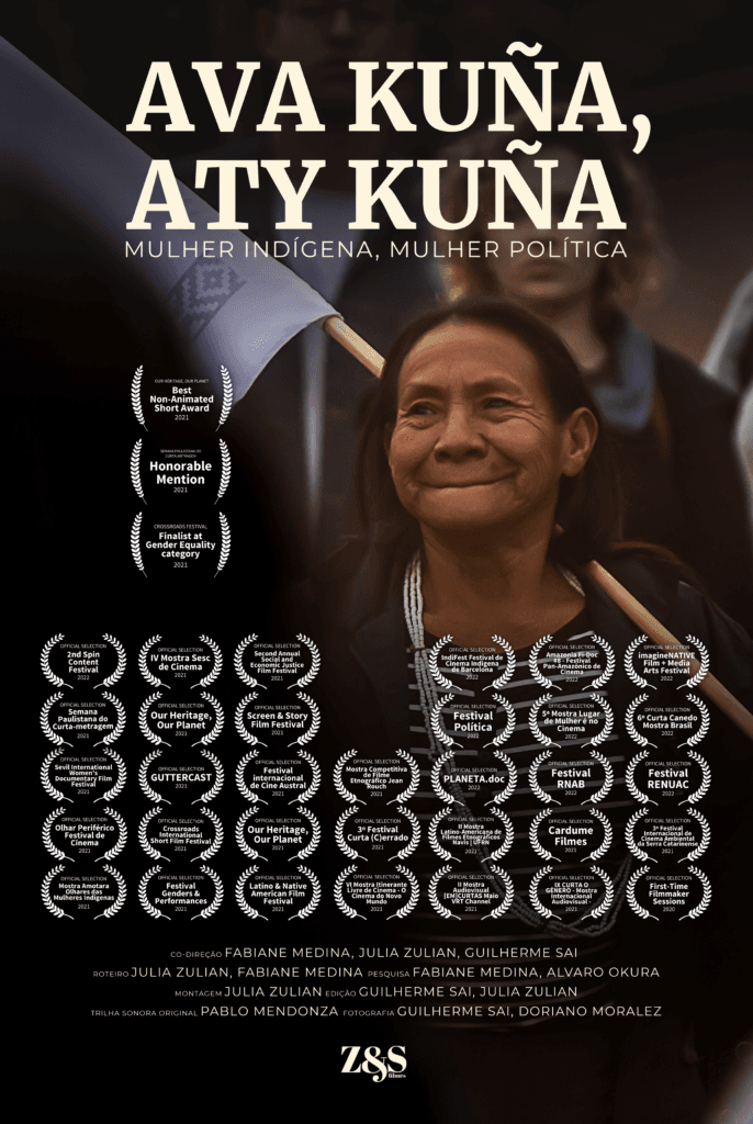 Cartaz do filme “Ava Kuña, Aty Kuña - Mulher Indígena, Mulher Política”. O destaque da imagem é uma mulher indigena sorrindo e segurando uma bandeira que é mostrada parcialmente. O título da obra está escrito na parte superior da imagem com letras amarelas de tom bem claro. A maior parte do cartaz apresenta vários selos de premiações representados por coroas de louros brancas. Na parte inferior, há os nomes dos participantes da equipe e elenco da obra, logo abaixo há a logo da Z&S