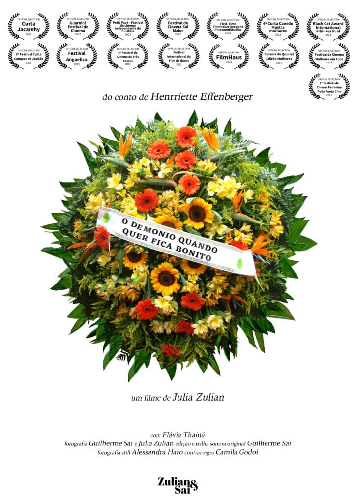 Cartaz do filme “O demônio quando quer fica bonito”. Apresenta o fundo totalmente branco e centralizado uma coroa de flores em tons de amarelo e laranja, com uma faixa em branco escrito o título da obra na cor preta. Na parte superior, há vários selos de premiações representados por coroas de louros na cor preta e abaixo o texto “do conto de Henriette Effenberger”. Abaixo da coroa de flores há os textos “um filme de Julia Zulian” e o nome de alguns participantes da equipe técnica da obra, todos escritos na cor preta. Na parte inferior, há a logo da Zulian&Sal.